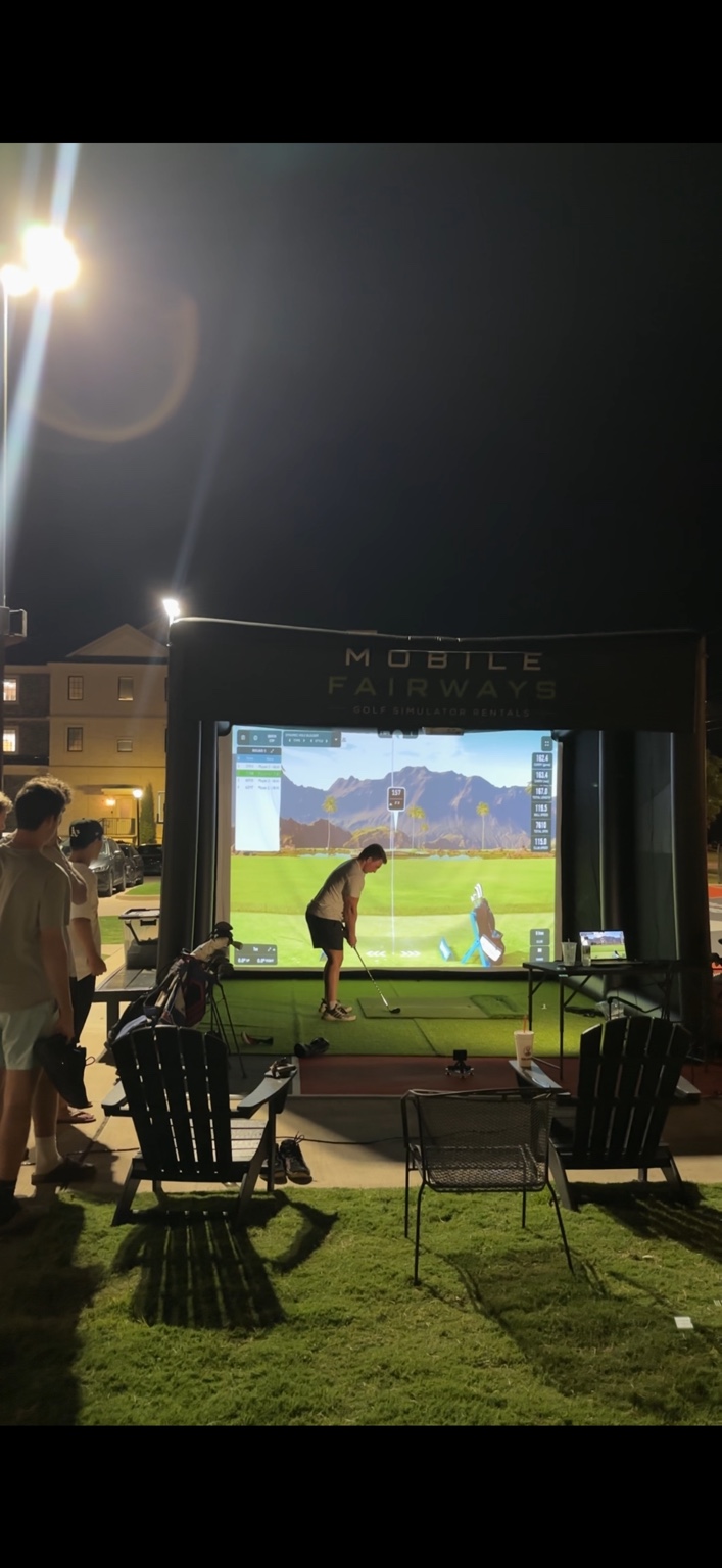 Guests gathered around the Mobile Fairways simulator during evening play