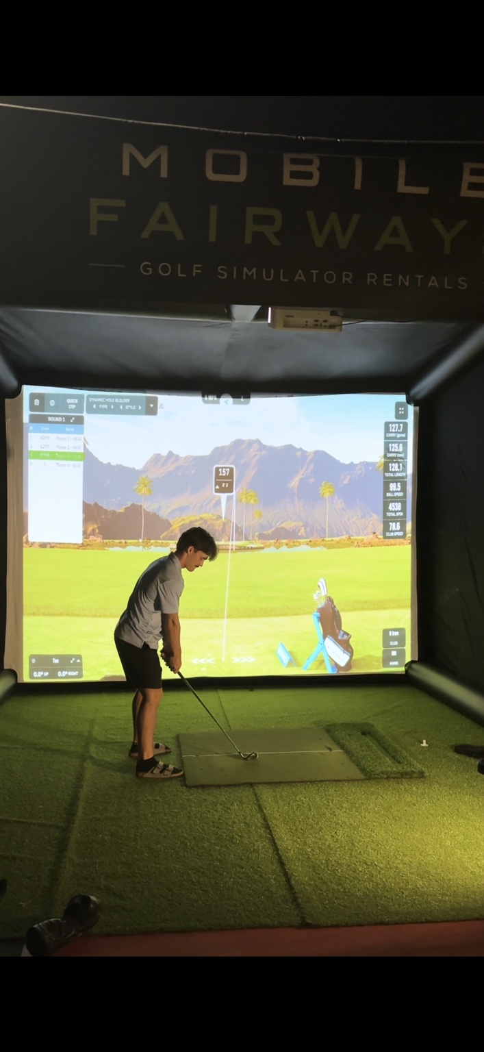 A guest taking a shot inside the Mobile Fairways simulator bay