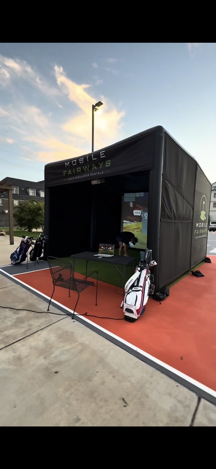 Angled view into the Mobile Fairways simulator with golf clubs ready for guests